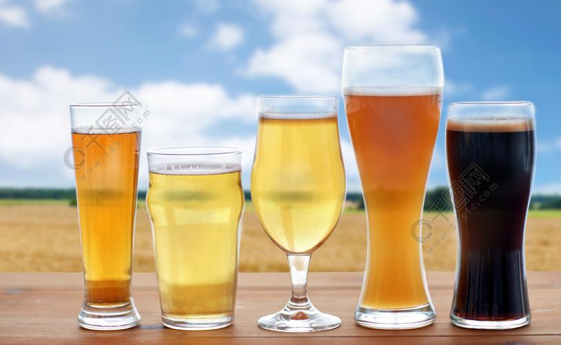 啤酒厂,饮料和酒精的概念— —啤酒在桌上麦田和蓝蓝的天空背景上的